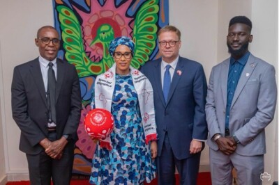 The First Lady of The Gambia stands in the center holding a red Special Olympics ball with Special Olympics representatives.