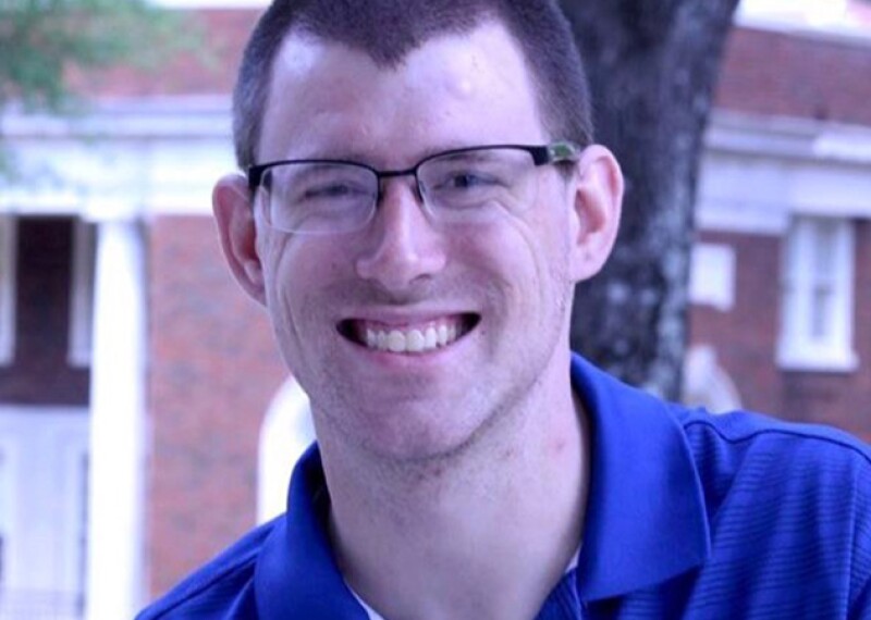 RJ smiling for a photo; he has on glasses and a blue polo. 