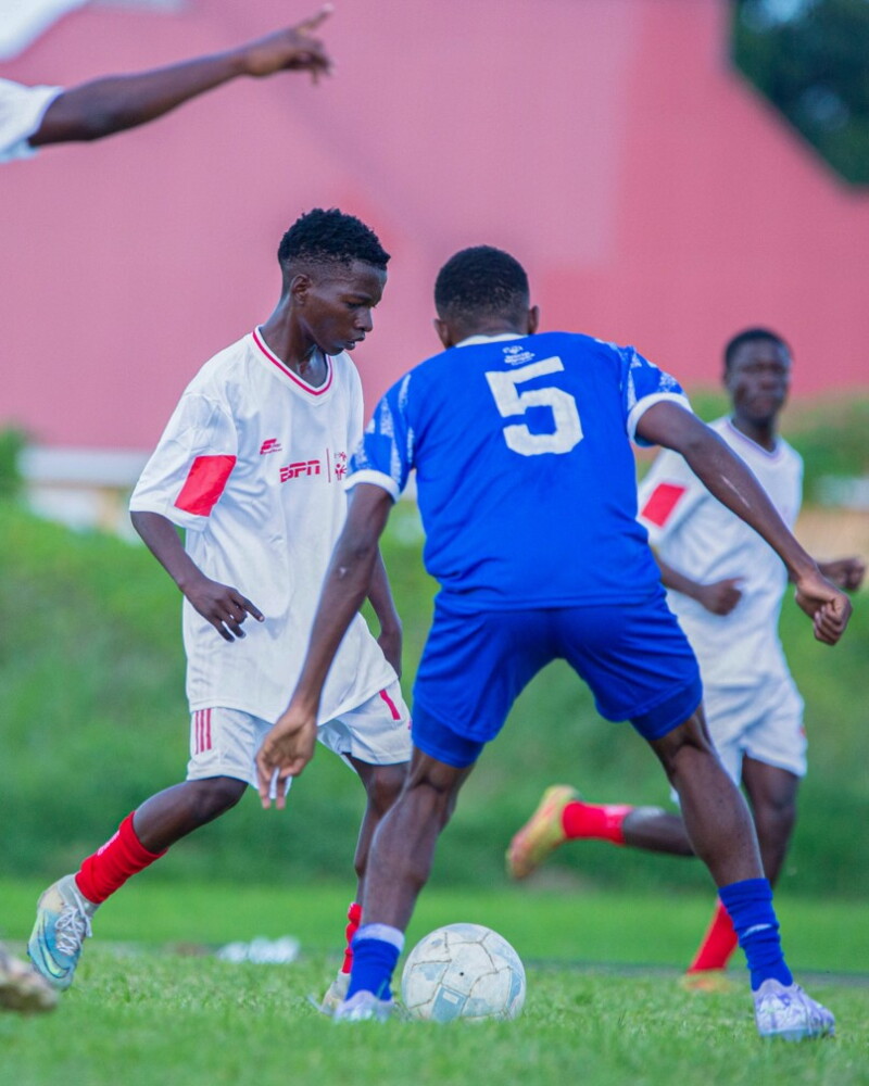 Footballers on the field, two players from opposing teams are going for the ball. 