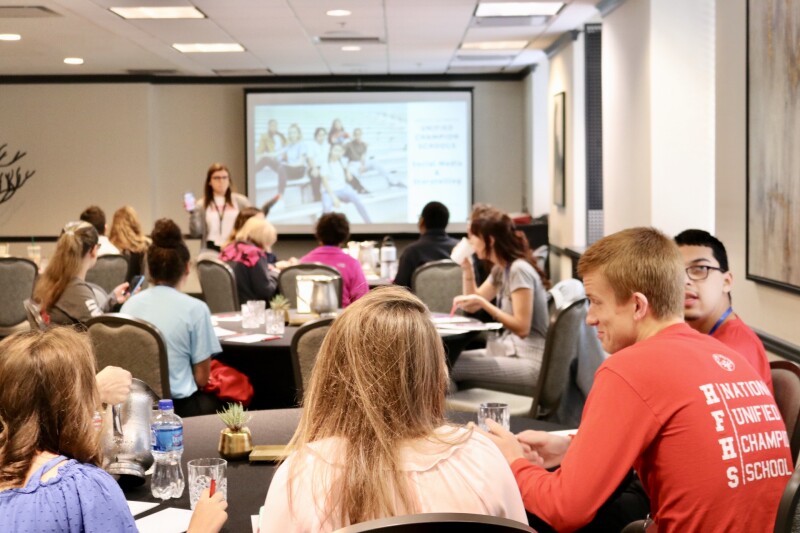 Students sitting at tables looking at a presentation