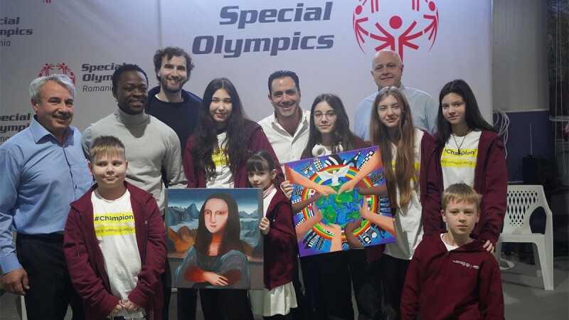 A group of people standing in front of Special Olympics signage. 