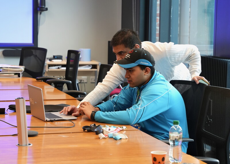 Two people at a table working on a computer. 