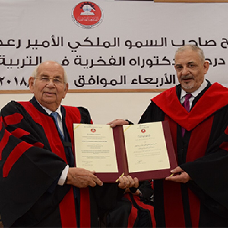 Dr. Bani Hani accepting an award. he's wearing a black and red graduation robe.
