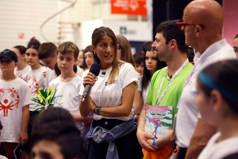 A woman holds a microphone as she chats to a man in a green t-shirt.