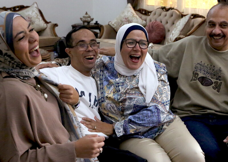 Family sitting on a couch laughing. 