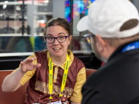 Young woman speaking and gesturing while a person pays attention. 