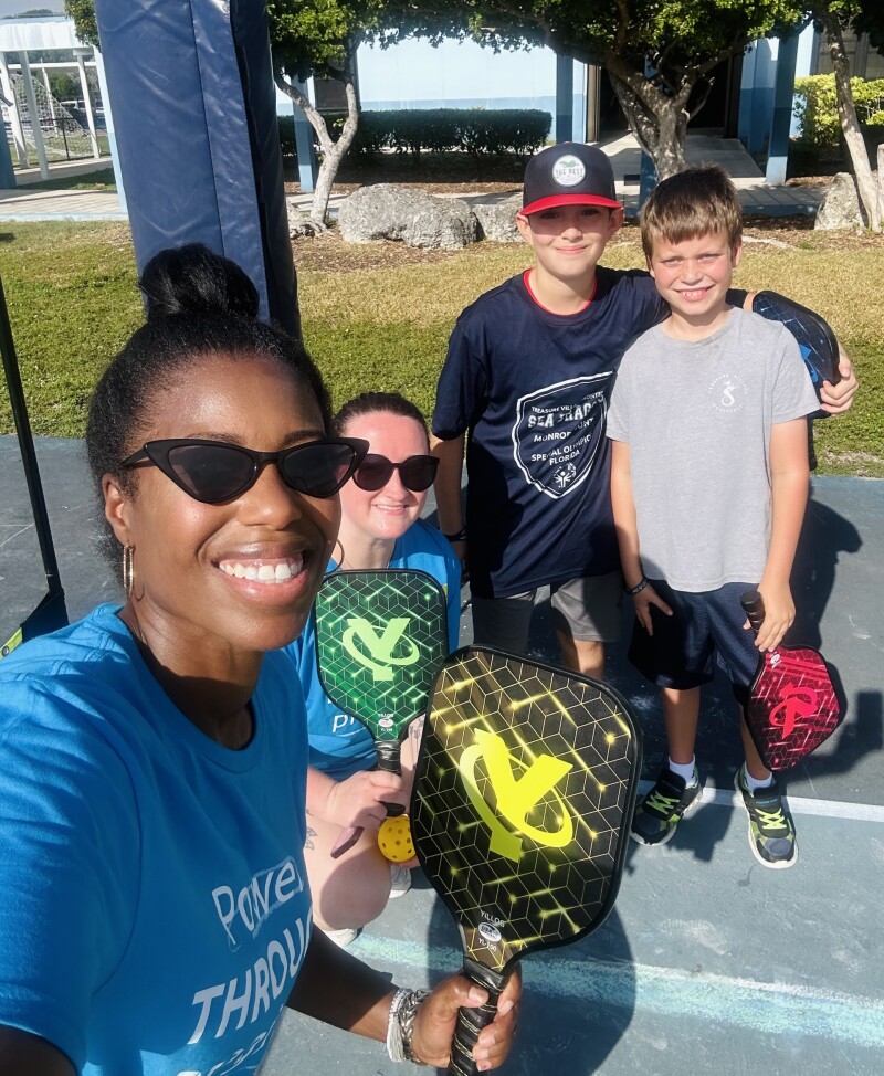 Cuatro personas afuera en un parque sonríen y están muy juntas. 