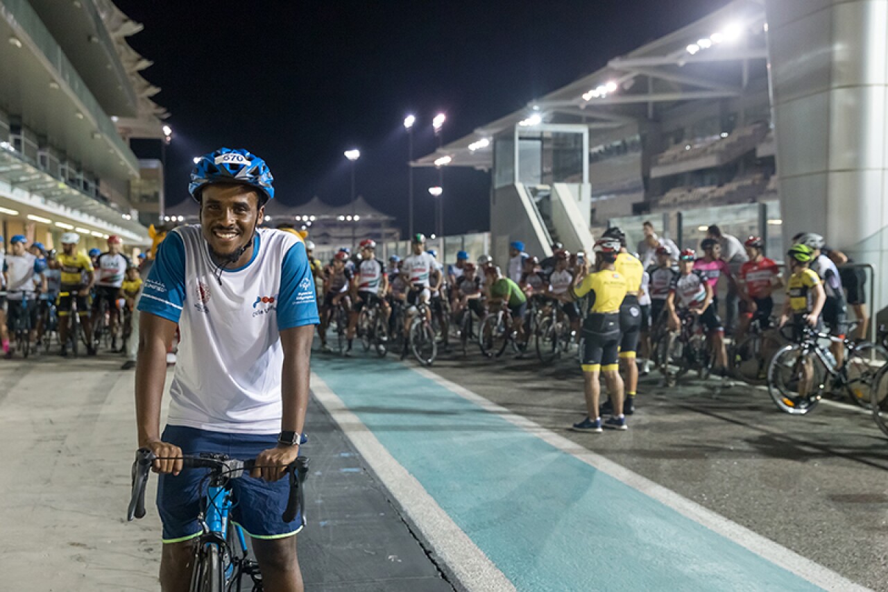 Unified athlete poses on his bicycle ahead of the starting line. Other cyclists are in the background.