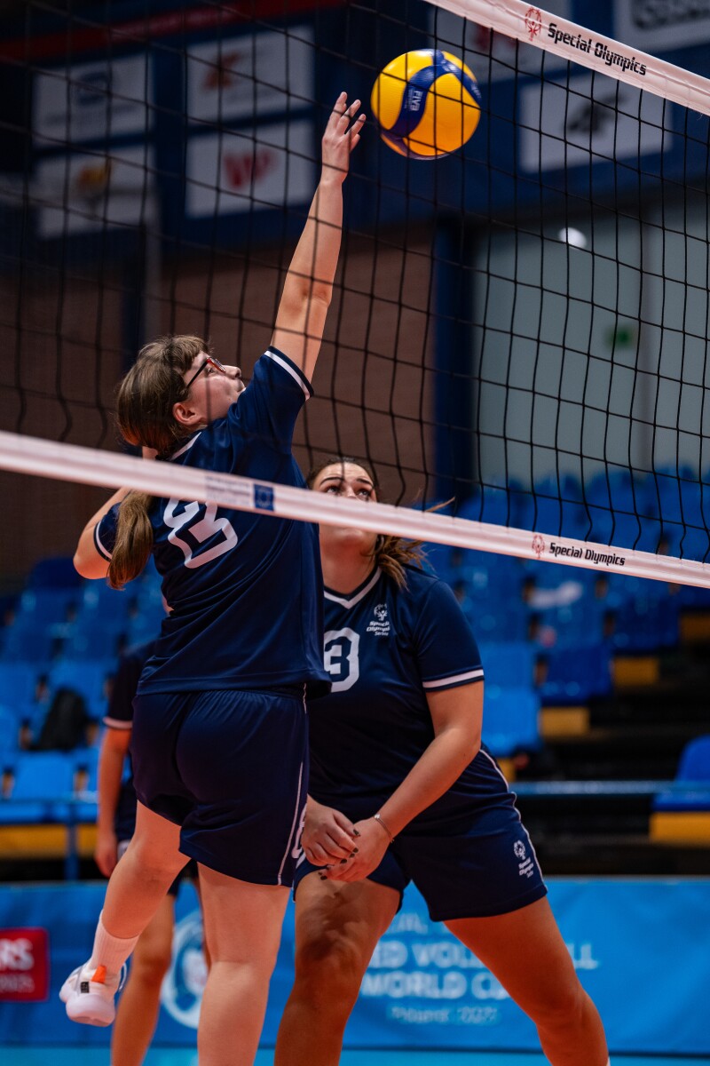 Marija attempts to hit the ball over the net as her teammate stands ready to assist