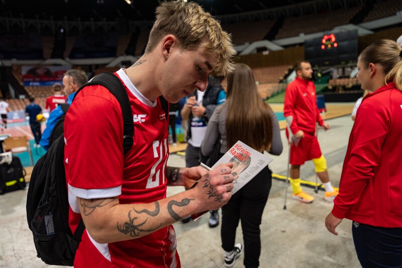 Krystian signs a magazine with his face on it