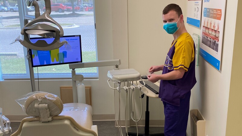 Ethan in the dental office standing by the equipment.
