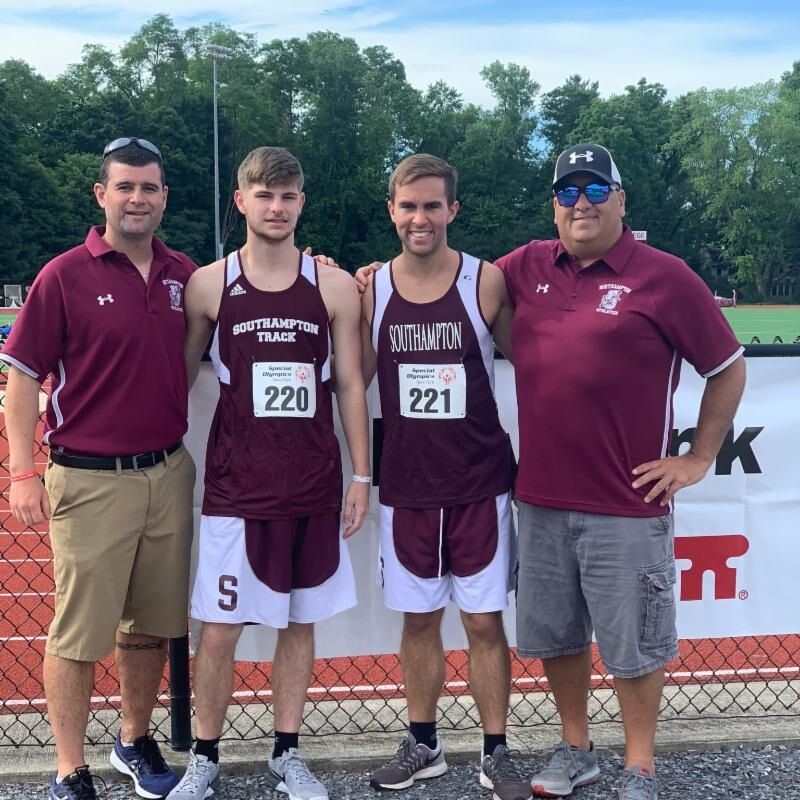 Coach Brian (left) with two Special Olympics New York athletes and coach at an athletics competition at Southampton High School in New York, USA.