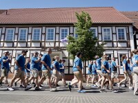 People in blue shirts and khaki pants walking in a single file line. 