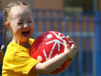 Special Olympics young female athlete smiling while holding a football.