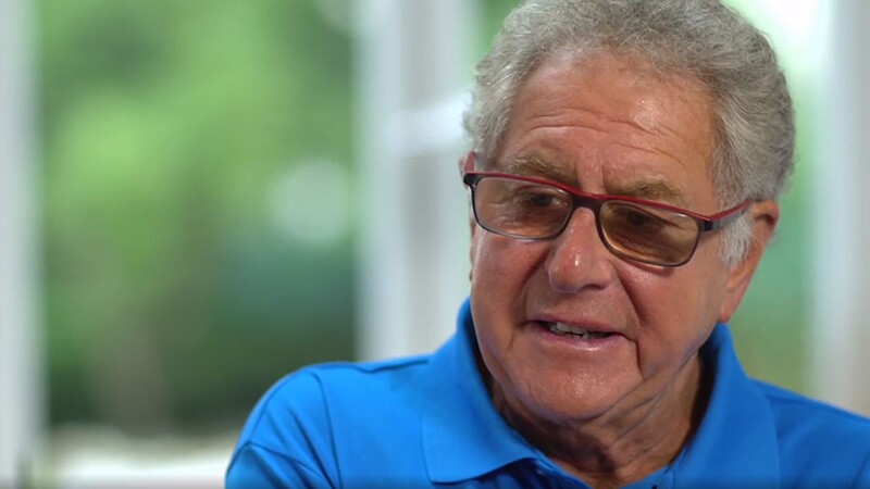 Doctor Richard Perlman sitting for an interview. He has on an blue polo shirt. 
