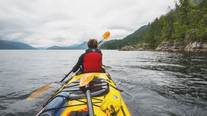Female kayaker paddling into the openness of the lake.