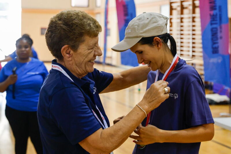 A woman awarding a medal to a young woman 