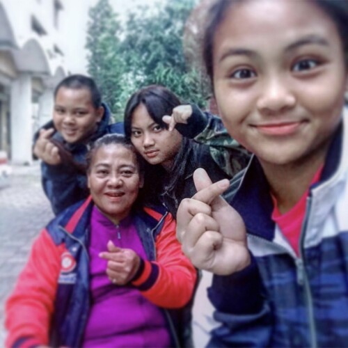 Ku Yu-Hsuan and others making hearts with their fingers while posing for a group photo around Ku’s mother, Chen