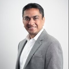 Seshasaye Kanthamraju in a gray suite and white button up shirt.