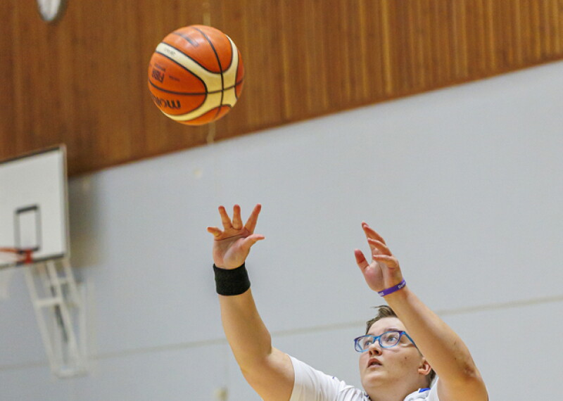 Female basketball player jumping and throwing a basketball