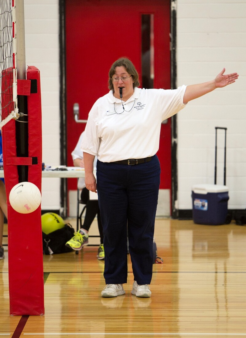 Kristine Hughes on the floor refereeing a volleyball match.