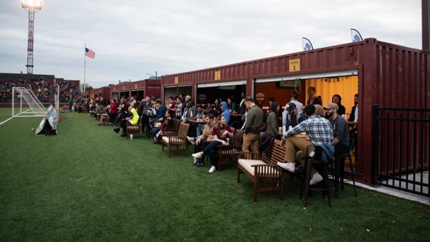 Spectators in boxes and on the bleachers watching a game.