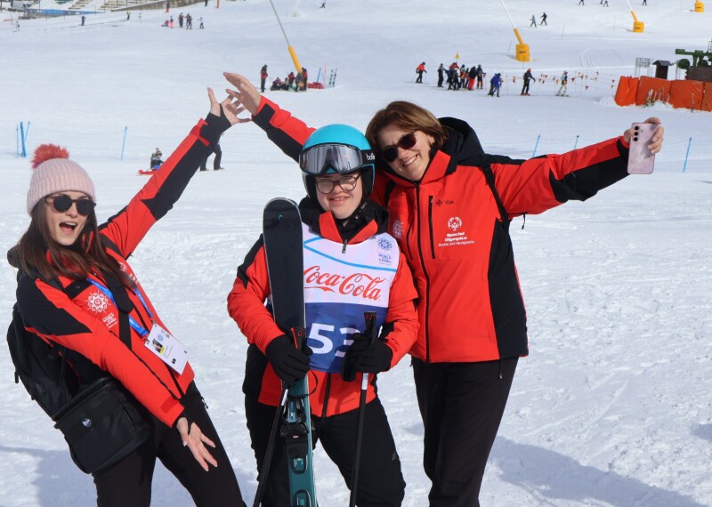 A athlete standing with two people smiling and enjoying the day outside in the snow. 