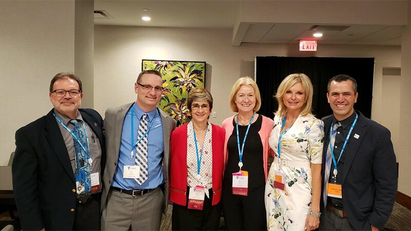 Six professionals standing side by side in a small group for a photo.