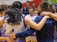 Bosnian team gathers on basketball court to celebrate and a female team member smiles