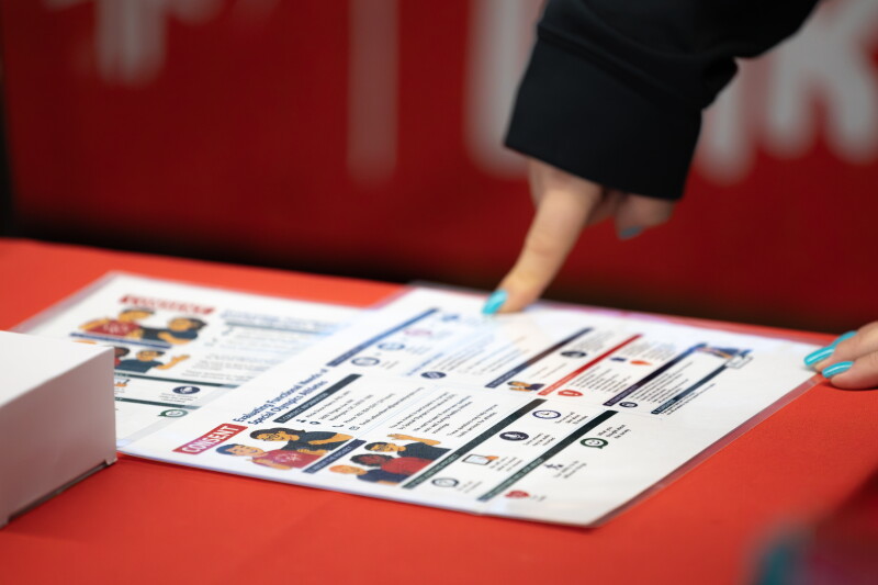 A person pointing down at an info graphic that is sitting on a table. 
