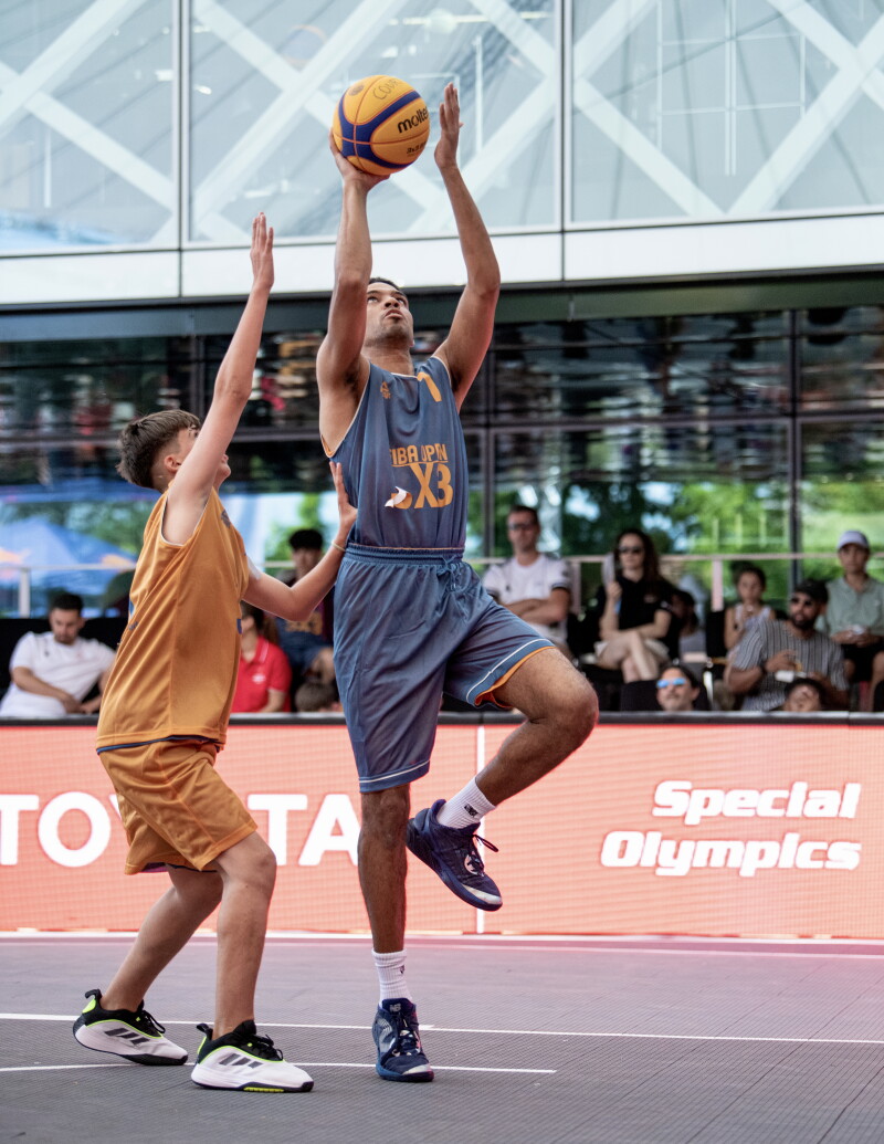 Two basketball players vie for the ball on court. 