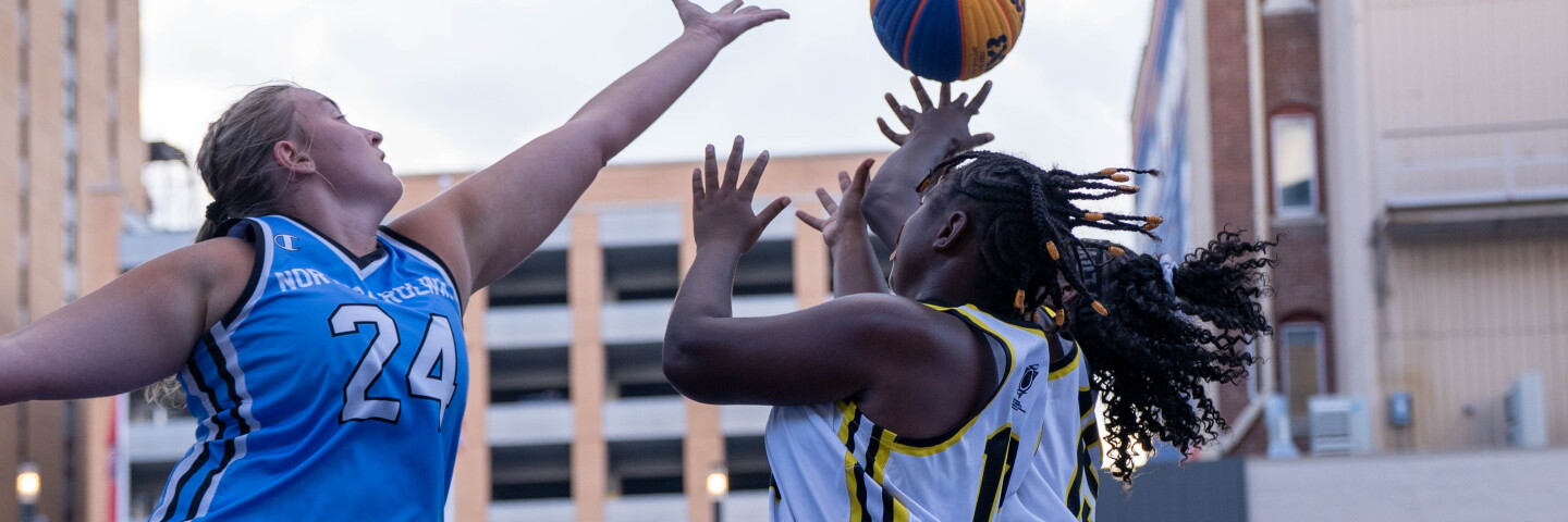 Three young women jumping for the basketball at tipoff. 