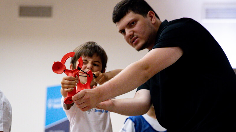 An adult helping a young boy to aim