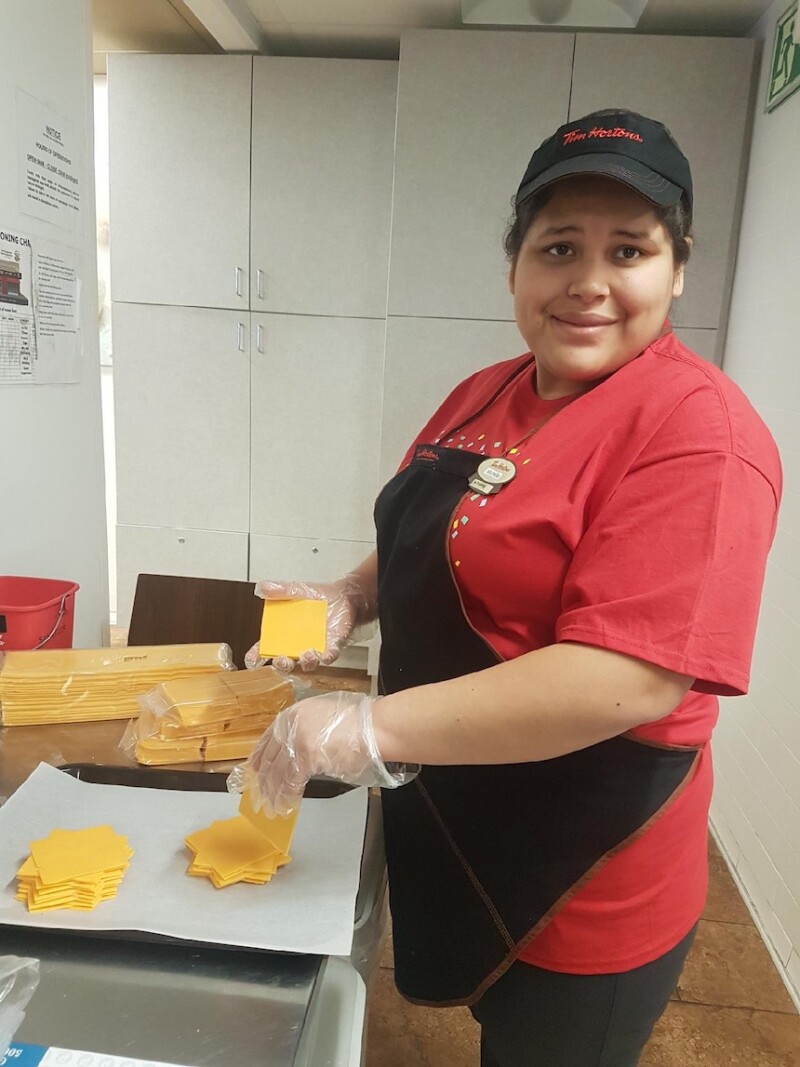A woman stands at counter in a kitchen. She's preparing food. 