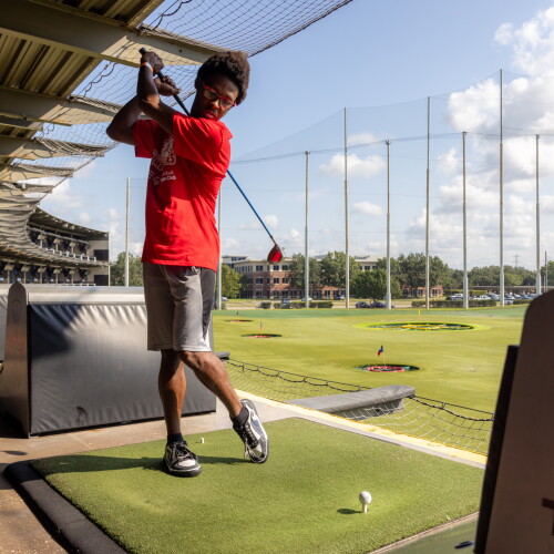 An athlete taking a swing at Topgolf. 