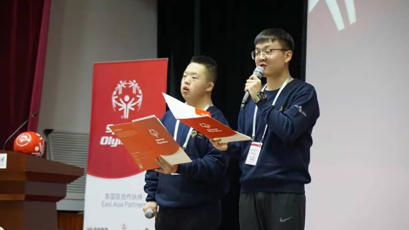 Yang Le on stage with another young man that is speaking. 