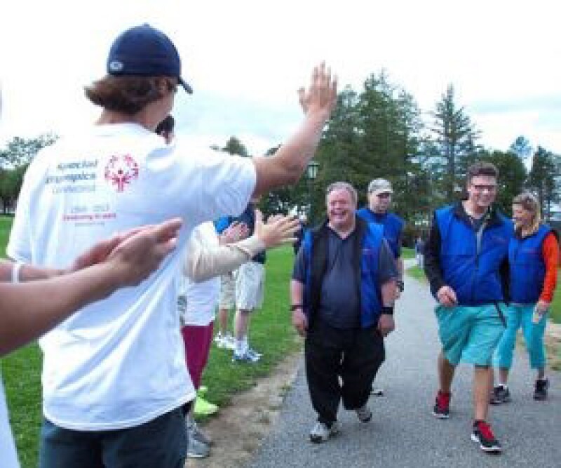 Unified Partner with his back to the photo is greeting a small group of athletes and Unified Partners from Special Olympics walking toward him at a Unified Fitness Club. 