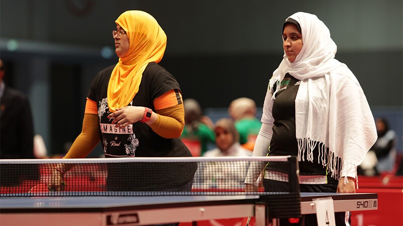 Khadija (left) and Mariem (right) standing at the table tennis table awaiting the competition to start.