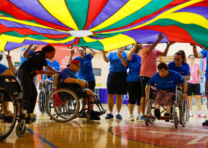 A group of athletes waving a huge, colourful cloth over their heads