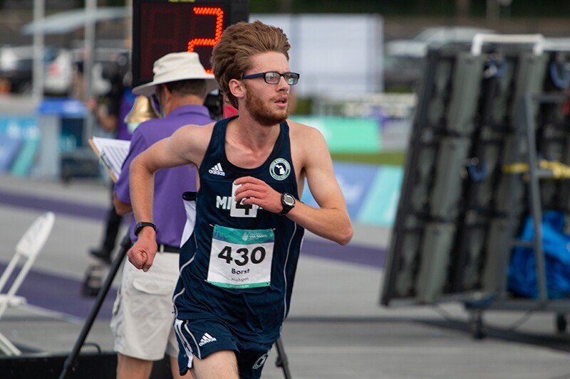 Man running in blue Adidas running shorts and tank top; his bib reads 430. 