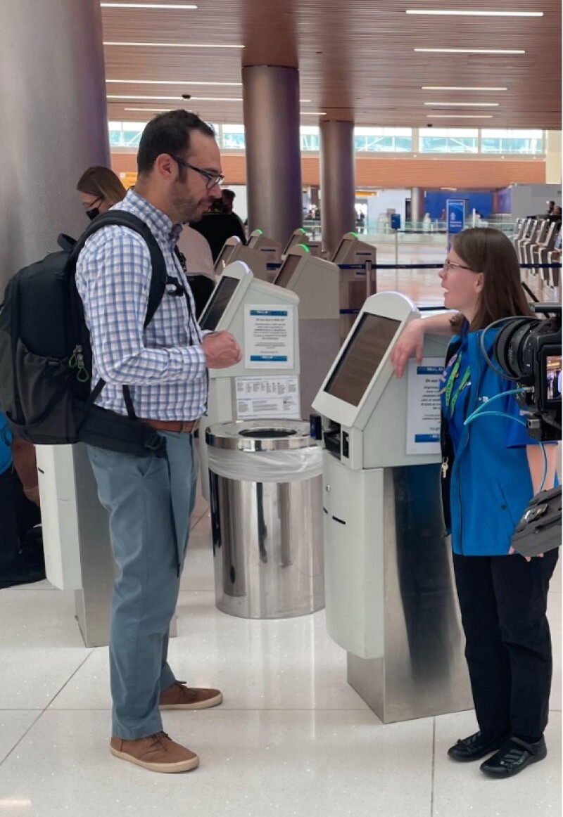 Two individuals stand at an airline check-in counter.