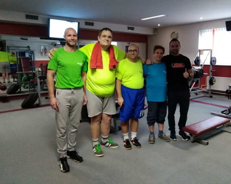 Special Olympics coaches and athletes stand in a gym in work-out gear. 