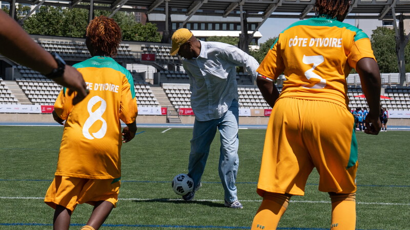 A man kicks a football with a group of football players