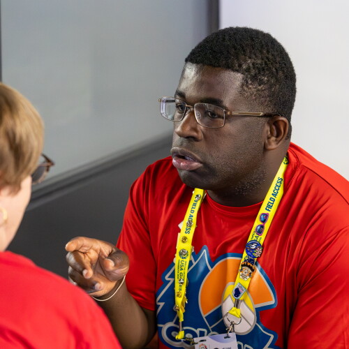 Man speaking and gesturing while a woman listens. 