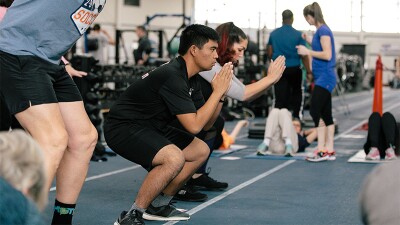 Athletes squatting and working out in a gym. 