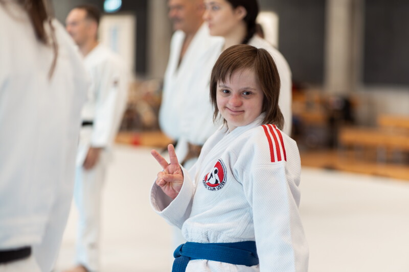A young woman wearing a judogi and making a peace sign