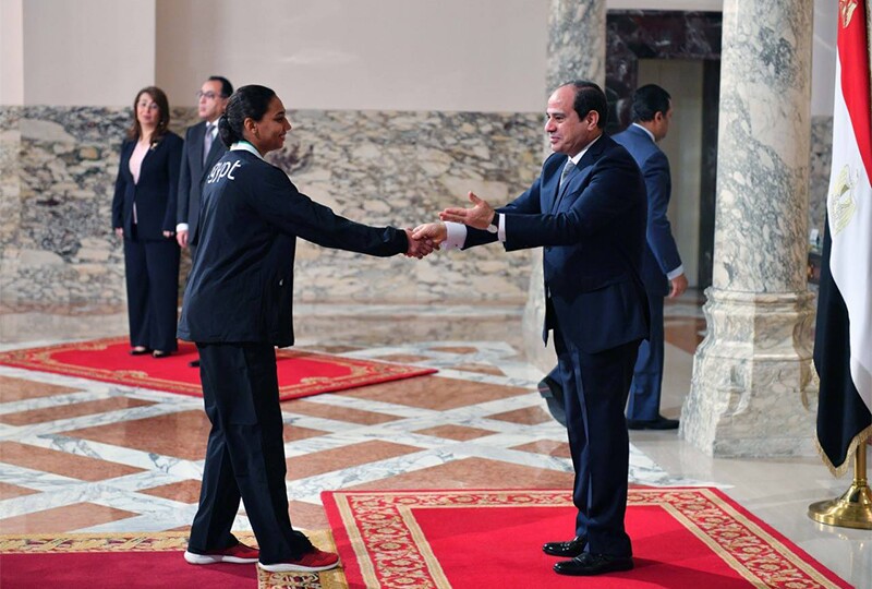 The Egyptian president shakes hands with a female athlete to recognize her achievement.