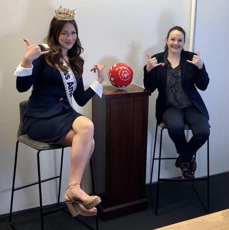 Two women sit in chairs, posing for a photo.