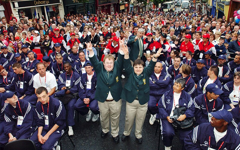 Large crowd of people in the streets sitting on chairs.