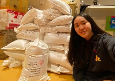 Isabelle sitting in a storage facility next to bags of rice.